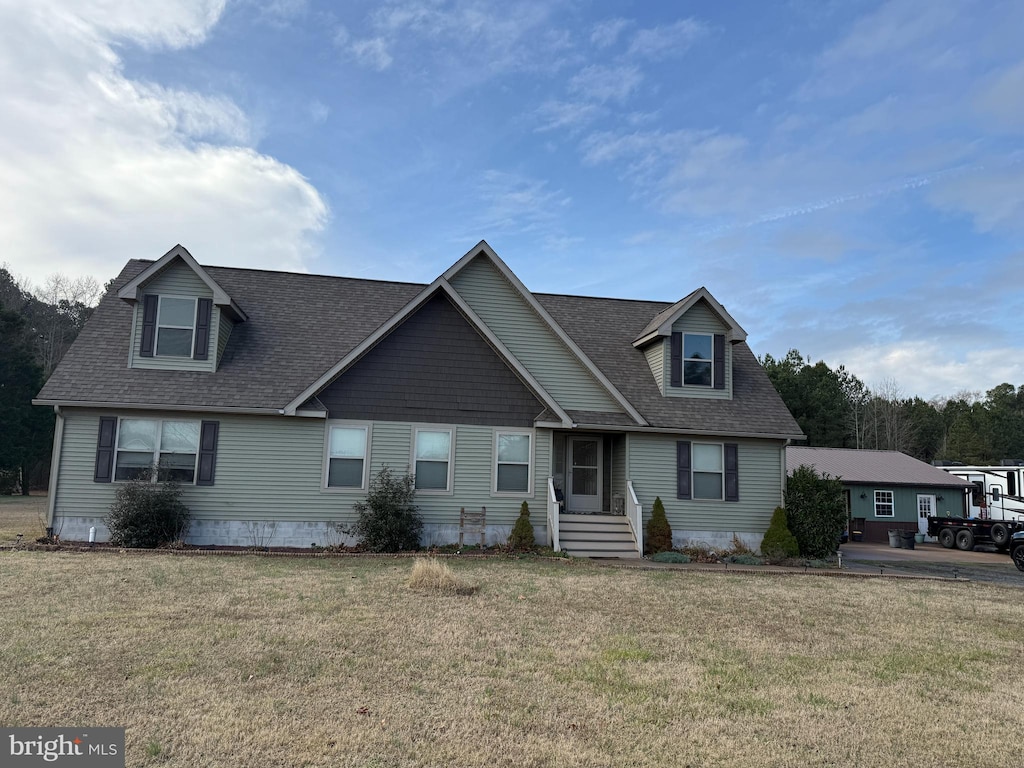 view of front facade featuring a shingled roof and a front yard