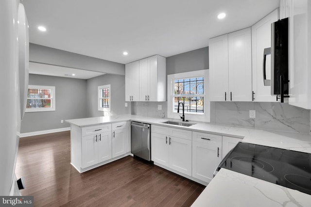 kitchen with sink, stainless steel dishwasher, white cabinetry, dark hardwood / wood-style flooring, and kitchen peninsula