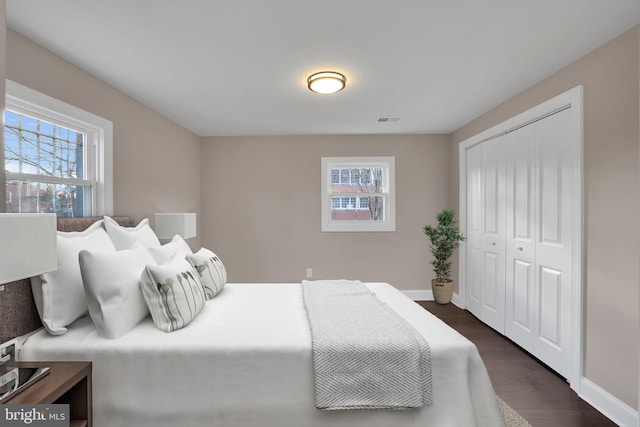 bedroom with multiple windows, a closet, and dark hardwood / wood-style floors