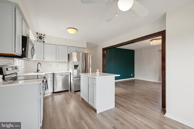 kitchen featuring a kitchen island, light wood-type flooring, backsplash, and appliances with stainless steel finishes