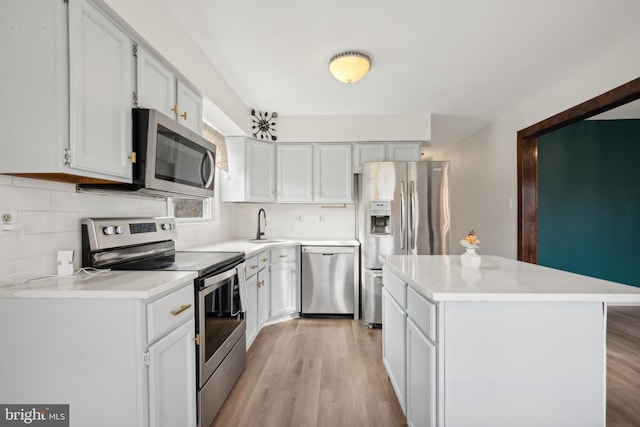 kitchen featuring white cabinetry, a center island, sink, stainless steel appliances, and light hardwood / wood-style flooring