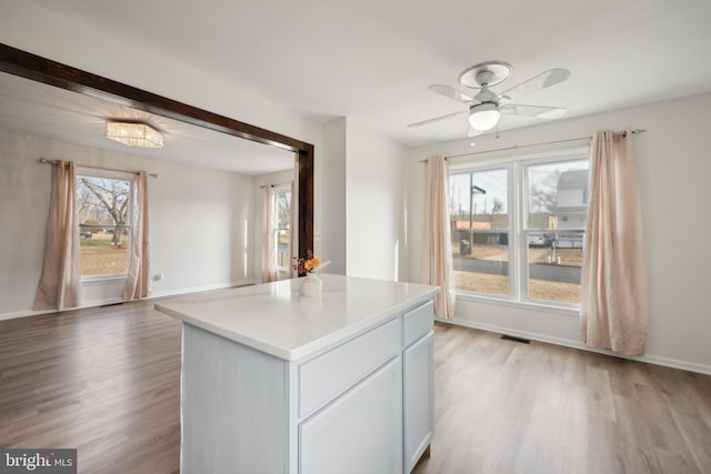 kitchen with white cabinets, light hardwood / wood-style flooring, ceiling fan, and a kitchen island