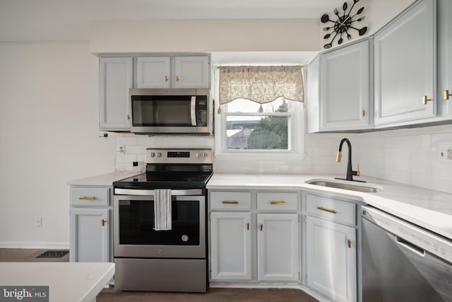 kitchen with backsplash, white cabinets, sink, and appliances with stainless steel finishes