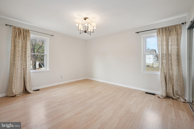 spare room with light hardwood / wood-style floors and a chandelier