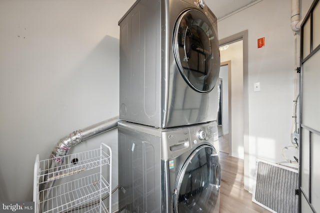 clothes washing area with light wood-type flooring and stacked washing maching and dryer