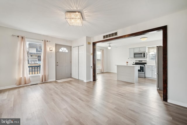 entryway with ceiling fan with notable chandelier and light wood-type flooring