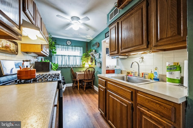 kitchen with ceiling fan, sink, dark hardwood / wood-style flooring, decorative backsplash, and stainless steel range with gas stovetop