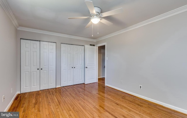 unfurnished bedroom featuring ceiling fan, light hardwood / wood-style flooring, two closets, and ornamental molding