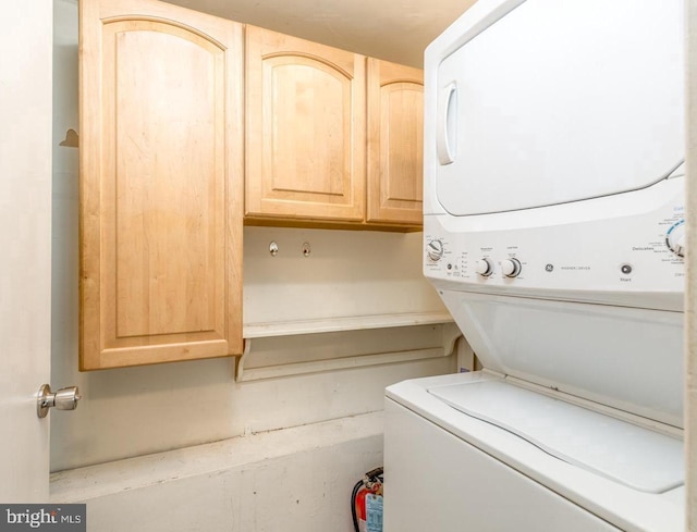 laundry area featuring cabinets and stacked washer / dryer