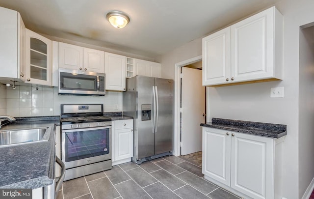 kitchen featuring white cabinets, backsplash, sink, and appliances with stainless steel finishes