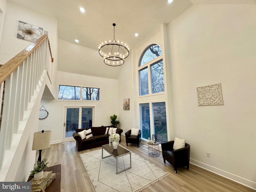 living room with an inviting chandelier, french doors, high vaulted ceiling, and light hardwood / wood-style flooring