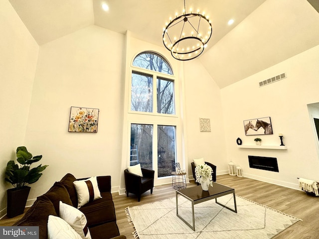 living room featuring wood-type flooring, high vaulted ceiling, and an inviting chandelier