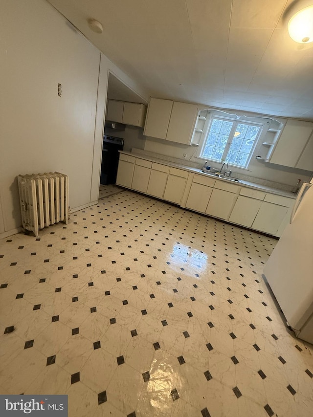 kitchen featuring white cabinetry, radiator heating unit, lofted ceiling, and sink