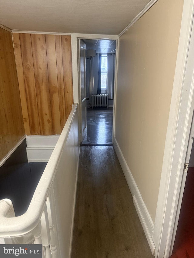 hallway featuring wood walls, radiator heating unit, and dark wood-type flooring