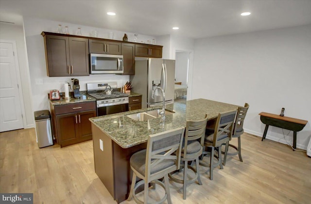 kitchen featuring appliances with stainless steel finishes, light wood-type flooring, a center island with sink, and sink