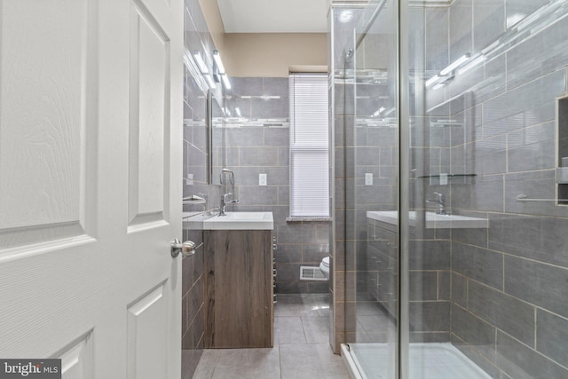 bathroom with walk in shower, tile patterned flooring, toilet, vanity, and tile walls