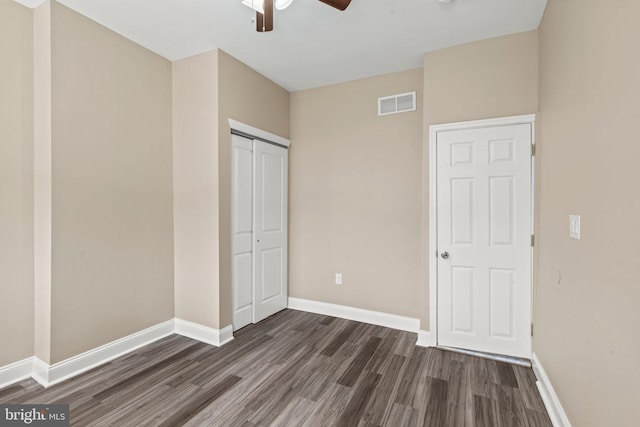 unfurnished bedroom featuring a closet, dark hardwood / wood-style floors, and ceiling fan