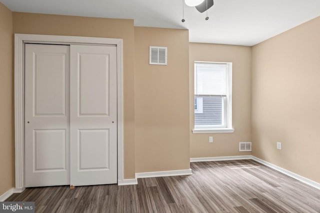 unfurnished bedroom featuring ceiling fan, a closet, and hardwood / wood-style flooring