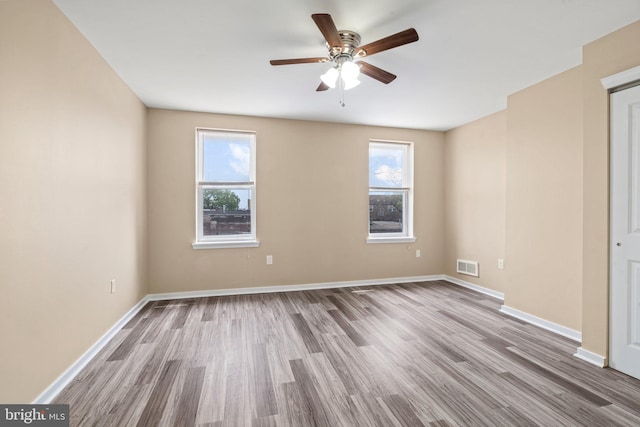 empty room featuring ceiling fan, a healthy amount of sunlight, and hardwood / wood-style flooring