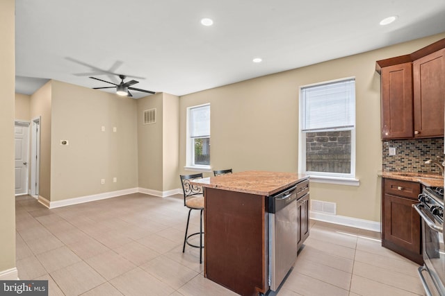 kitchen featuring appliances with stainless steel finishes, a center island, light stone counters, and a healthy amount of sunlight