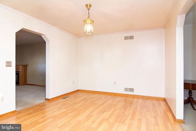 spare room with hardwood / wood-style flooring, an inviting chandelier, and ornamental molding