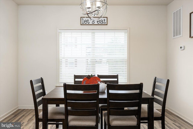 dining area with hardwood / wood-style floors and a notable chandelier