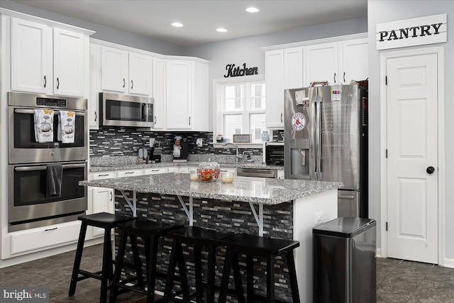 kitchen featuring white cabinets, a kitchen breakfast bar, a center island, and stainless steel appliances