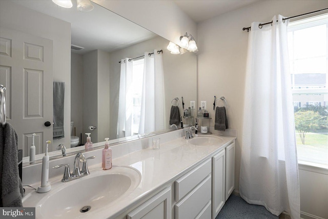 bathroom with vanity, a healthy amount of sunlight, and toilet