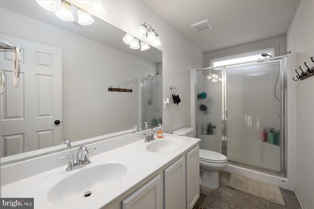 bathroom featuring tile patterned floors, vanity, a shower with shower door, and toilet