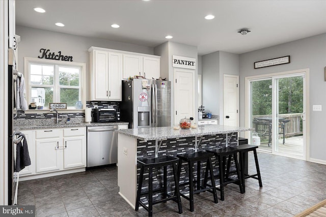 kitchen featuring a kitchen island, light stone countertops, a healthy amount of sunlight, and appliances with stainless steel finishes