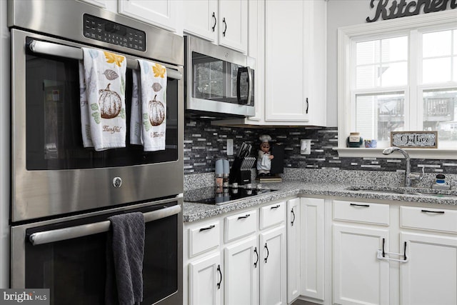 kitchen featuring sink, stainless steel appliances, light stone counters, decorative backsplash, and white cabinets