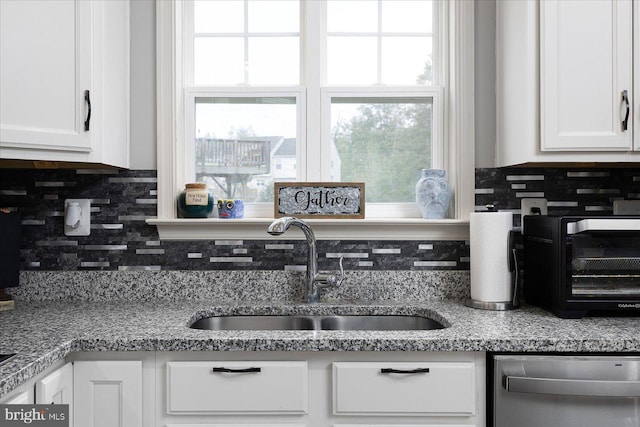 kitchen with dishwasher, decorative backsplash, white cabinetry, and sink