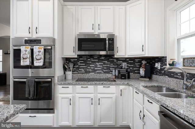 kitchen featuring tasteful backsplash, white cabinetry, sink, and appliances with stainless steel finishes