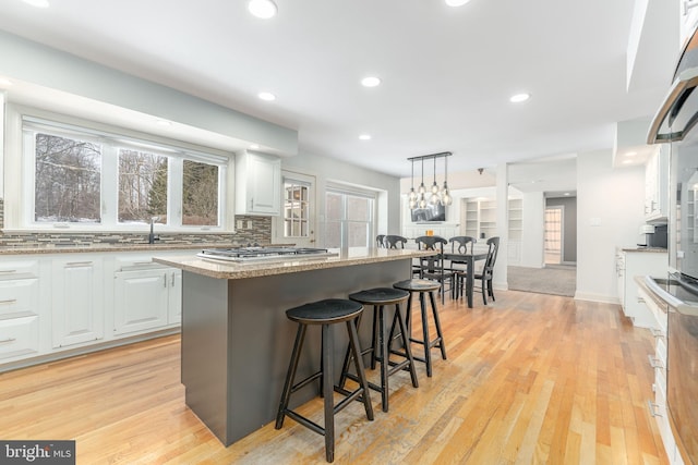 kitchen with a kitchen bar, decorative light fixtures, white cabinets, and a kitchen island