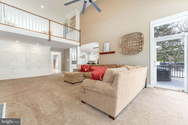 carpeted living room with a towering ceiling and ceiling fan