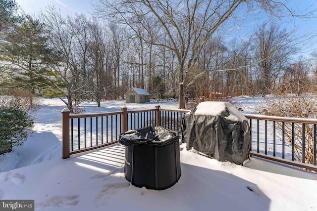 snow covered deck with a storage unit and a grill