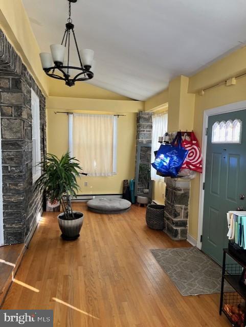 interior space with an inviting chandelier, lofted ceiling, and hardwood / wood-style flooring