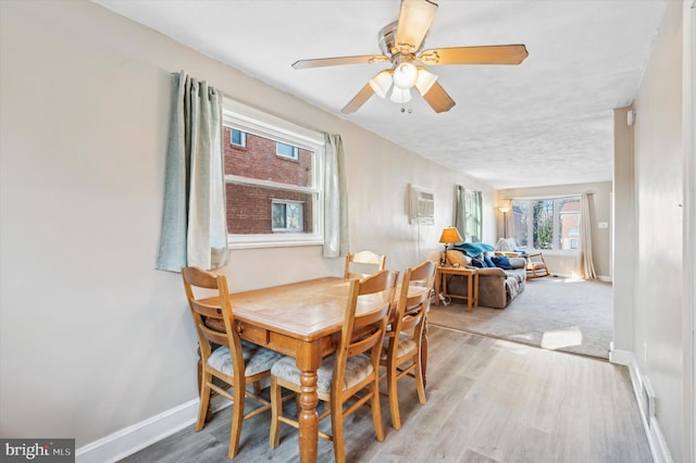 dining room featuring a wall unit AC, ceiling fan, and hardwood / wood-style flooring