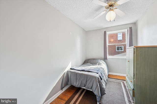 bedroom featuring a textured ceiling, ceiling fan, and dark hardwood / wood-style flooring