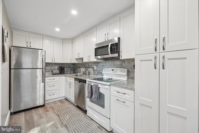 kitchen featuring light hardwood / wood-style flooring, stainless steel appliances, white cabinetry, and light stone counters