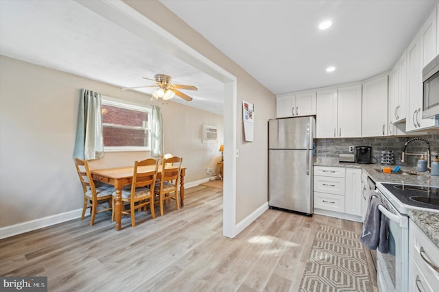 kitchen featuring electric range, light stone countertops, stainless steel fridge, white cabinets, and tasteful backsplash