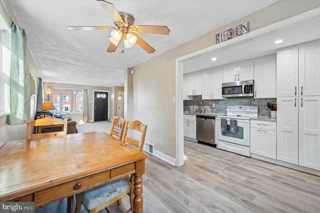 dining space with ceiling fan, light hardwood / wood-style flooring, and sink