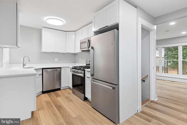 kitchen with white cabinetry, sink, stainless steel appliances, and light wood-type flooring