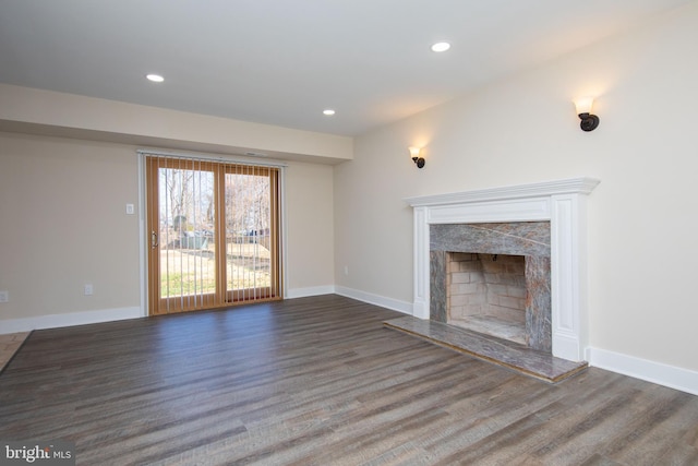 unfurnished living room featuring a premium fireplace and dark hardwood / wood-style flooring