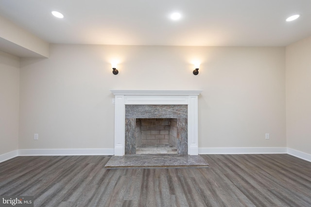 unfurnished living room with a premium fireplace and dark wood-type flooring