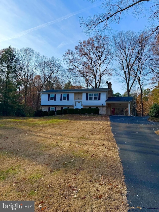 raised ranch featuring a carport and a front lawn