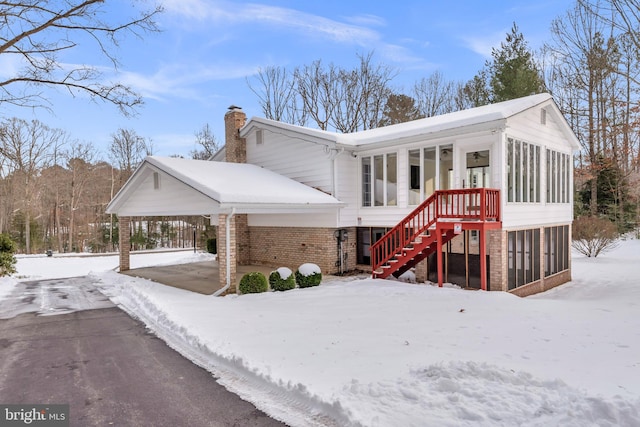 view of front of home with a sunroom and a carport