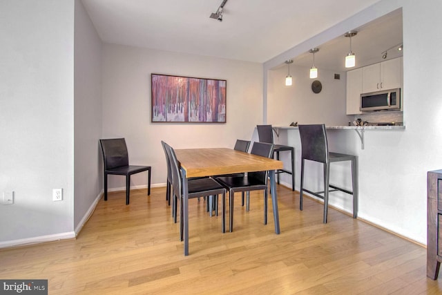 dining space with track lighting and light hardwood / wood-style flooring