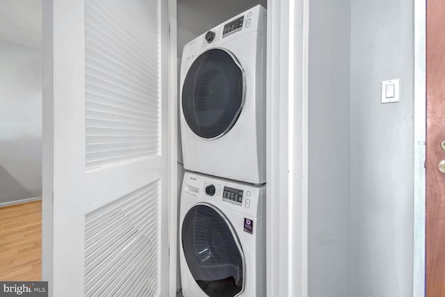 clothes washing area featuring stacked washer / drying machine and wood-type flooring