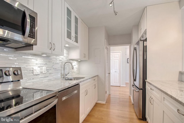 kitchen featuring sink, light hardwood / wood-style flooring, appliances with stainless steel finishes, light stone counters, and white cabinetry